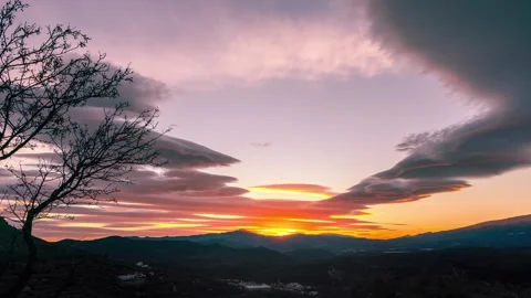 Timelapse of lenticular clouds with sun setting behind mountains HD H264 Stock Footage 312068422