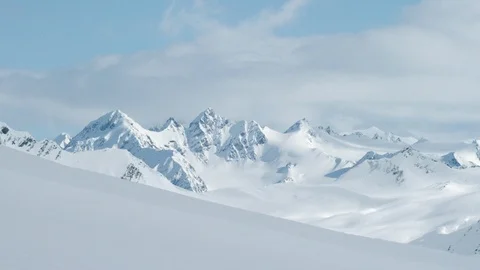 Timelapse of light cloud travelling across blue sky above snow covered mountains Stock Footage 124238373
