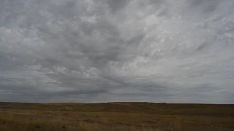 Timelapse of Light Gray Clouds Moving Toward the Viewer Above a Dry Prairie Stock Footage 331683812
