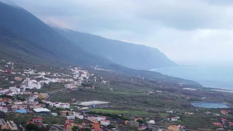 Timelapse of low clouds passing over a small town in an island Video stock 136899980