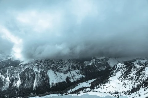 Timelapse of low lying clouds rolling over mountain tops in winter with snow. Stock Footage 127041912