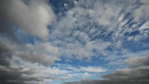Timelapse of low white and gray clouds moving through a blue summer sky Stock Footage 312076516