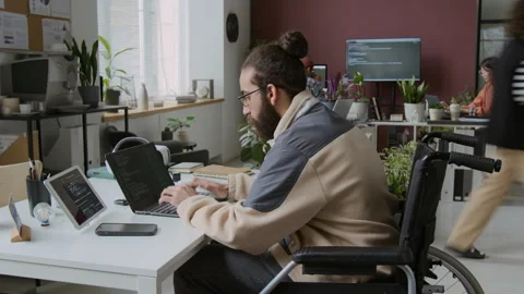 Timelapse of Male Programmer in Wheelchair Working on Code in Busy IT Office Stock Footage 285704426