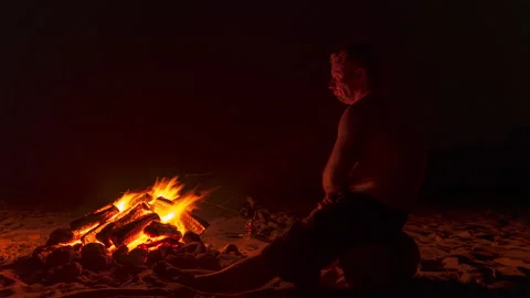 Timelapse of man sitting at a beach bonfire Stock Footage 159965189