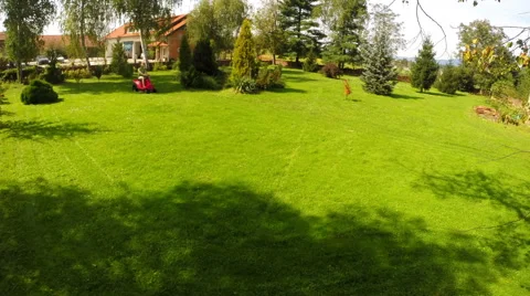 Timelapse of a man sitting on a lawn mower cutting grass on the lawn Stock Footage 44861400
