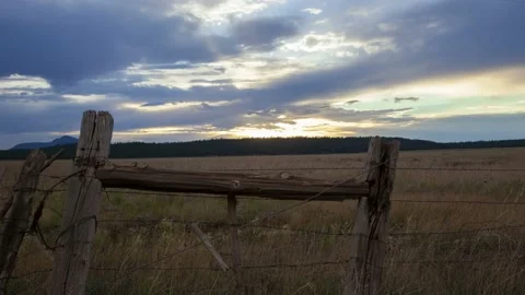 Timelapse of monsoon clouds and sunset beyond a rustic old ranch fence Stock Footage 201301355
