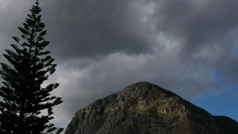 TimeLapse - Moody clouds gliding over sandstone mountain, big fir tree in Stock Footage 112112280