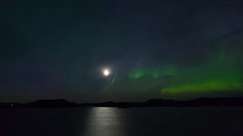 Timelapse of moon and aurora borealis over lake and craters at night Video stock 73011809