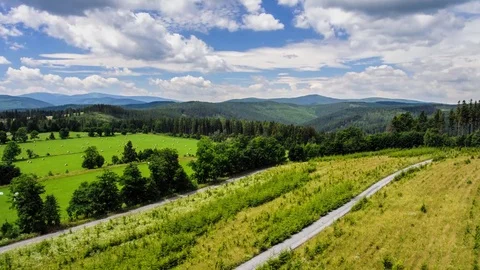 Timelapse mountain landscape path between fields and forrest against the sky Stock Footage