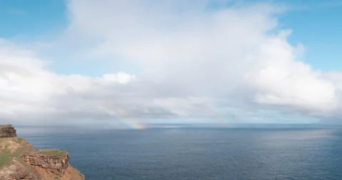 Timelapse with moving clouds and rainbow over the ocean in Madeira Stock Footage 231777388