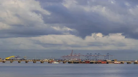 Timelapse of moving clouds over the industrial factories and piers by the sea Stock Footage 197524716