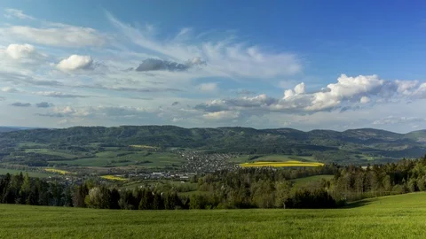 Timelapse of moving clouds over a village that lies in a mountain area Stock Footage 130089624