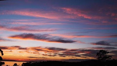 Timelapse of multi colored sunrise with whispy clouds over a lake lots of color Video stock 122437998