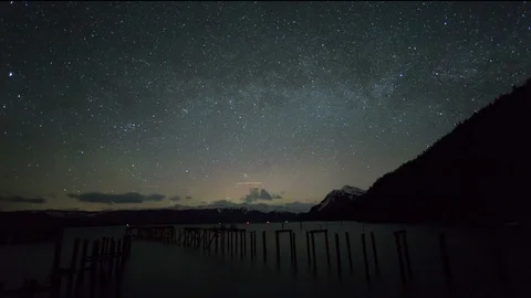 Timelapse of night sky being covered in shining stars above mountains and lake Stock Footage 129114834
