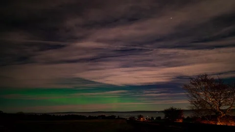 A timelapse of the northern lights on a Cloudy Moonlit winters night in cum.. Stock Footage 256593180