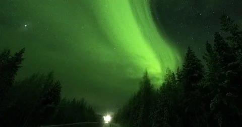 Timelapse of the Northern Lights over a forest road with moving cars. Stock Footage 147684696