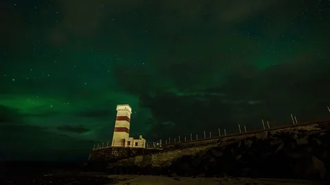 Timelapse of northern lights over lighthouse and a black sand beach at night Stock Footage 73011628