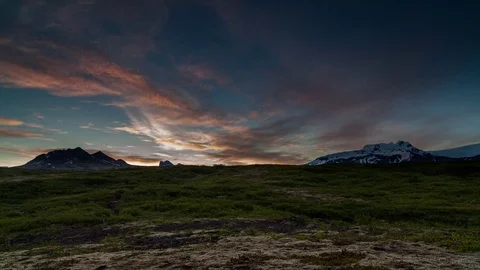 Timelapse of orange clouds rolling over snowy mountains and grassy landscape Stock Footage 73011655