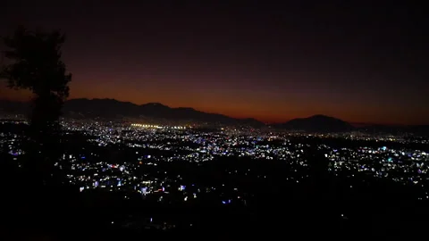 Timelapse of orange horizon of sunset with night city lights and mountain Stock Footage 248140486