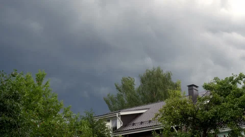 Timelapse of overweight heavy clouds over small houses, wind is blowing and now Stock Footage 221057111