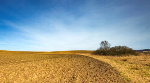 Timelapse of plowed field under blue sky with cirrus clouds.  Stock Footage 61094287