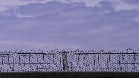 Timelapse of prison walls with barbed wire and moving clouds Stock Footage 75745452