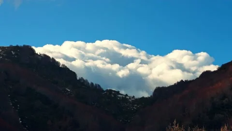 Timelapse of puffy clouds behind the mountains. 스톡 동영상 237077475