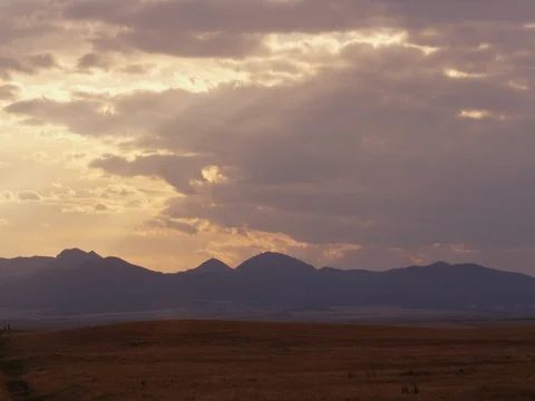 Timelapse - Purple clouds race over distant hills Video stock 81194513