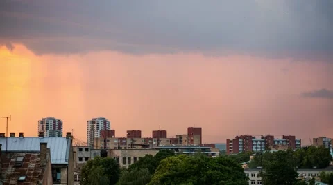A timelapse of rain clouds rushing over a city skyline at sunset Stock Footage 64602363
