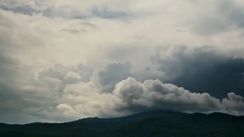 Timelapse of the rainy clouds moving in the blue sky above the hills Stock Footage 261491724