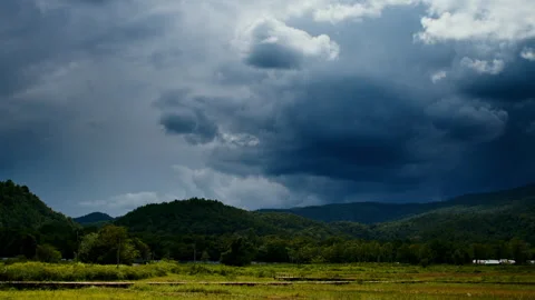 Timelapse of the rainy clouds moving in the sky above the green fields Stock Footage 261491579