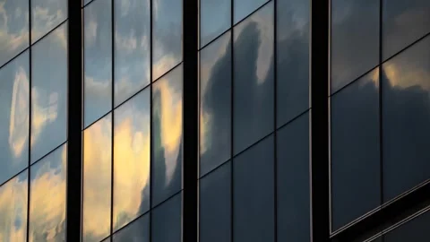 Timelapse reflection of moving clouds and blue sky in glass wall skyscraper Stock Footage 250287037