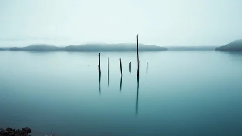 Timelapse of restless lake rippling back and forth as morning fog sits down Stock Footage 129114604