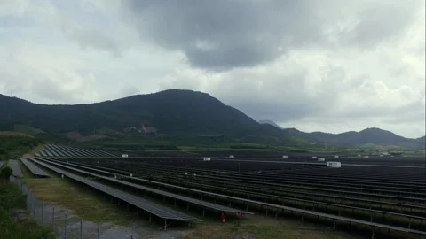 Timelapse reveals rows of solar panels across rolling green hills as clouds race Stock Footage 324838956