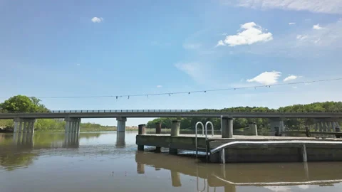 Timelapse of river and bridge over peaceful river and sky speckled with small Stockbeeldmateriaal 337180354