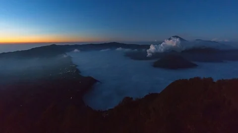 Timelapse of rolling cloud and smoke against mountain during sunrise in Bromo 動画素材 90528149