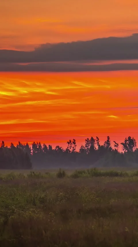 Timelapse shot of clouds passing over a silhouette field during sunset Stock Footage 317625393