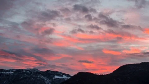 Timelapse shot of red clouds flowing on the snowy peaks at sunset, Julian Alps Stock Footage 89836185
