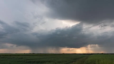 Timelapse showing storm clouds passing with visible rainfall over grain fields Stock Footage 303964960