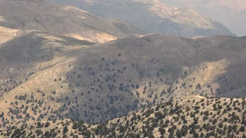 Timelapse shows cloud shadows drifting across rocky valleys - Mountain Terrain Stock Footage 339646837