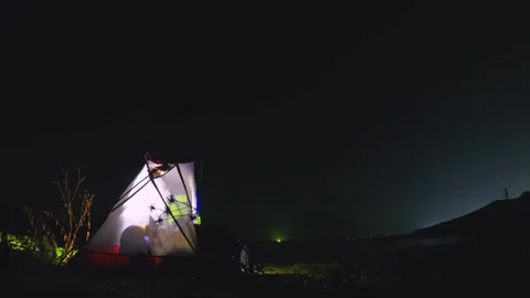 Timelapse of single tent with light inside and a woman laying down wild camping  Stock Footage 240483225