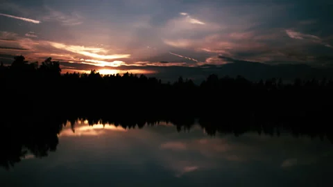Timelapse - The sinking red sun shines through the treetops in nature. A lake 스톡 동영상 164667482