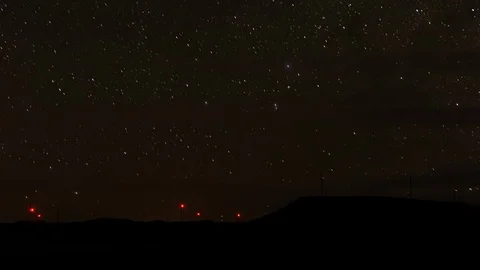 Timelapse of a sky of stars moving behind a field of wind turbines Stock Footage 101683140