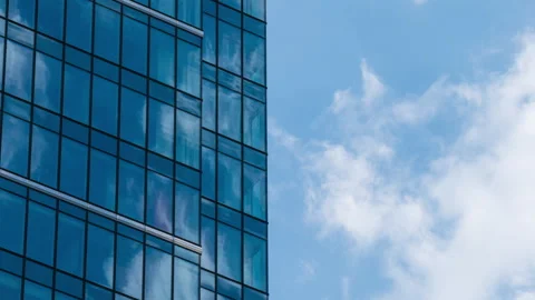 Timelapse of skyscraper glass facade reflecting moving white clouds in blue sky Stock Footage 335031040