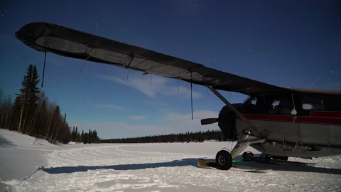 Timelapse of small airplane parked over night in snow, starry night above Stock Footage 129129903