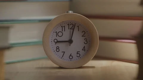Timelapse of a Small Analog Clock Amidst a Stack of Books Stock Footage 208804352