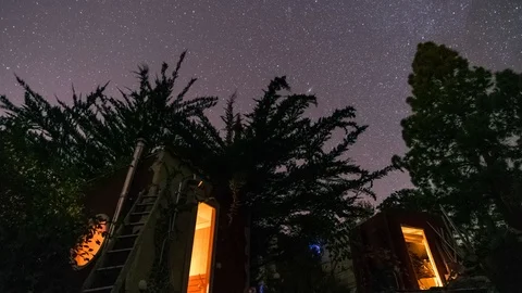 Timelapse of sparkling starry night sky moving above tree-house Stock Footage 99930543