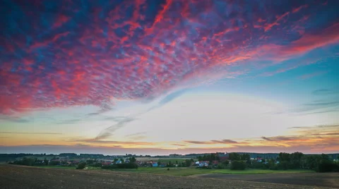Timelapse of spectacular sunset sky over plowed field and village. Stock Footage 58714006