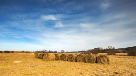 Timelapse of spring meadow with hay bales under blue sky with cirrus clouds. 库存影片 61094182