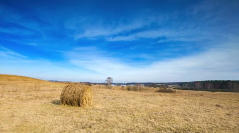 Timelapse of spring meadow with hay bales under blue sky with cirrus clouds.  Stock Footage 61094228